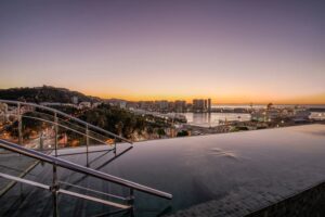 The infinity pool on the terrace of the luxury hotel, showcasing the incredible sunset and views of Málaga.