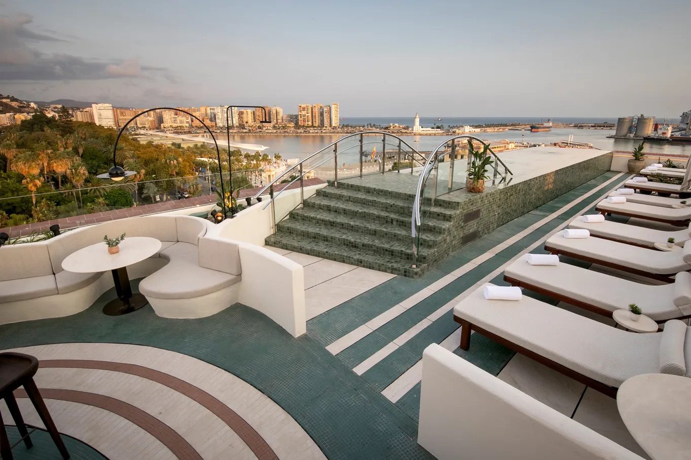 The terrace at the luxury hotel, featuring an infinity pool, comfortable seating and an array of sun loungers, all complete with incredible views over Málaga.