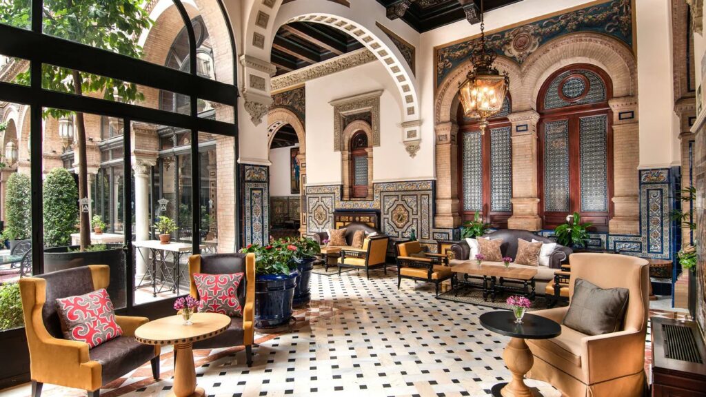 A seating area in the luxury hotel featuring a variety of armchairs, sofas and tables, complete with intricate architecture, arches, pillars and large windows letting in natural light.