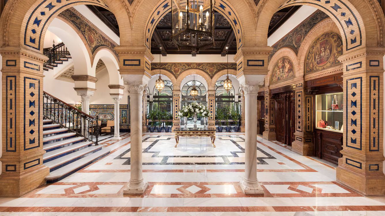 The grand lobby at the luxury Hotel Alfonso XIII, featuring archways, a large staircase and incredible architecture adorning the walls and ceiling.