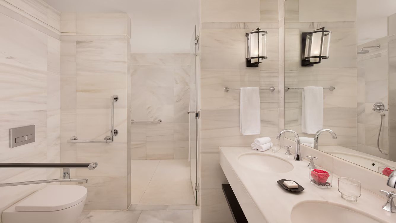 A bathroom in the luxury Hotel Alfonso XIII, featuring a double sink, toilet and walk in shower.