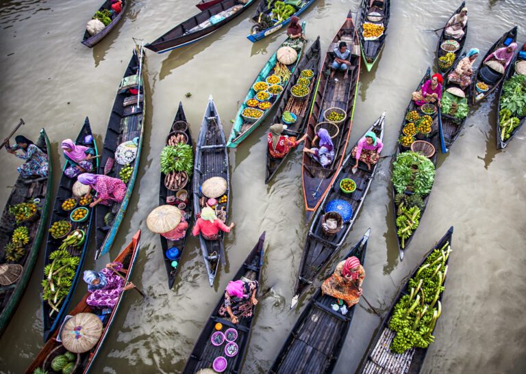 Image from above of long narrow wooden kayaks with brightly coloured local produce for sale at the floating market Lok Baintan, Banjarmasin, South Kalimantan, Indonesia mainly operated by women