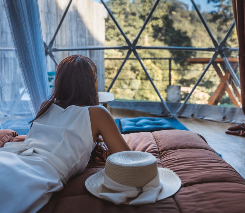 Woman travelling alone, is alone in a hotel room, looks out of the window.