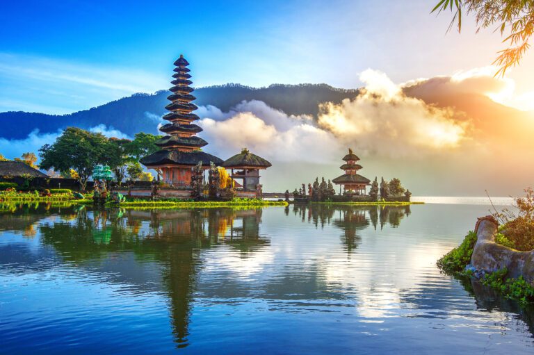 Pura Ulun Danu Bratan Temple in Bali, Indonesia. Temples appear on islands ona lake with mountains and clouds behind.