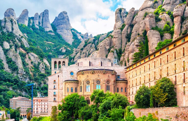 The Santa Maria de Montserra Abbey in Catalonia Spain shown with the dramatic rock formations of the mountainous region behind it