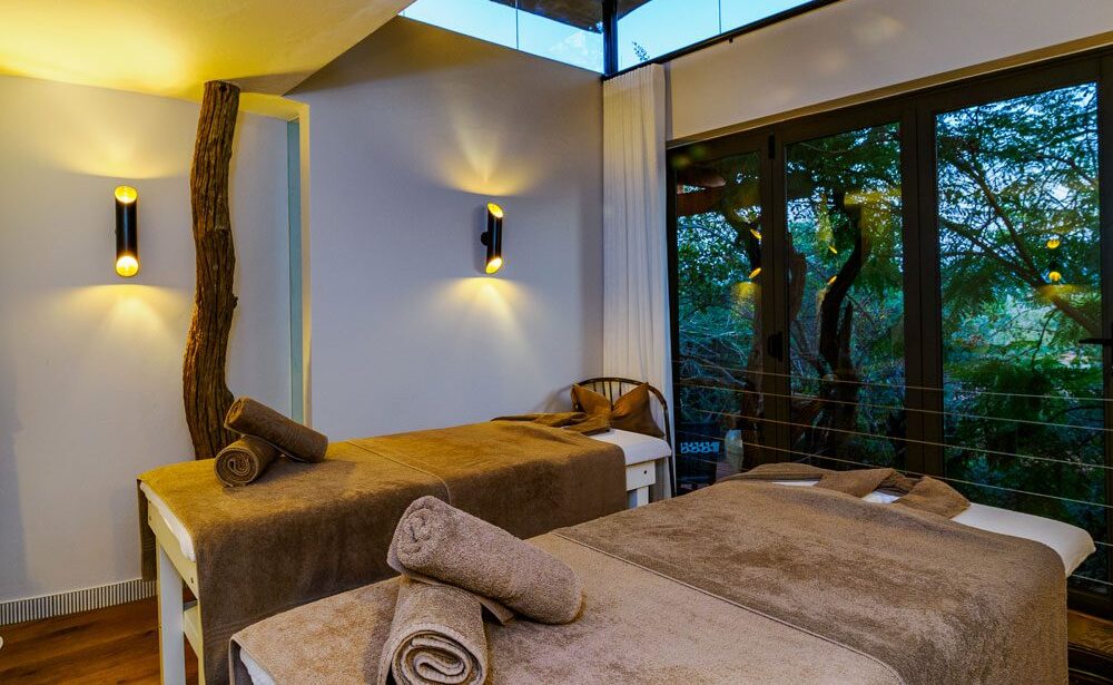 Two massage tables with towels covering the beds and a view of the safari outside.