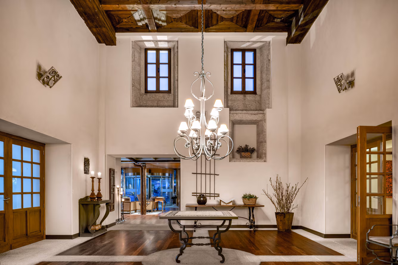 The foyer at the luxurious hotel with a low-hanging chandelier and wooden furnishings.