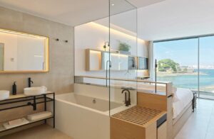 A bedroom in the luxury hotel featuring a sink, bathtub bed and large windows opening onto a private balcony.