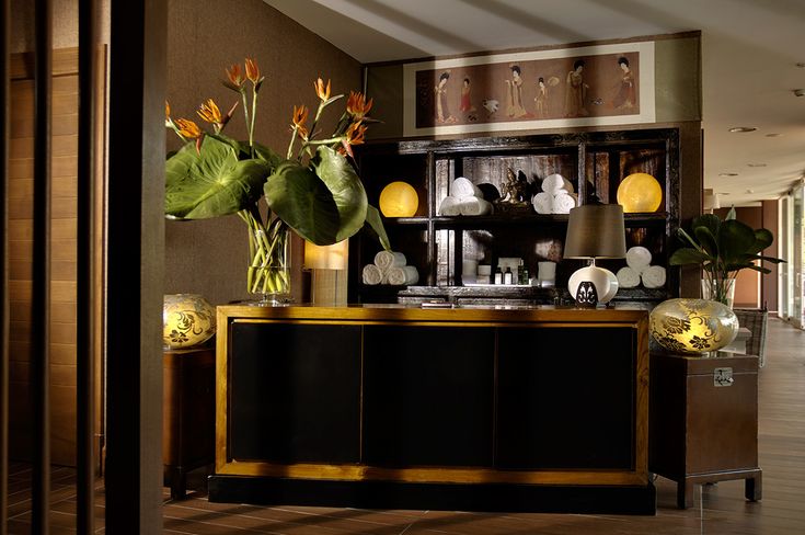 A reception desk of the luxury spa with flowers on the desk and towels on the shelf behind.
