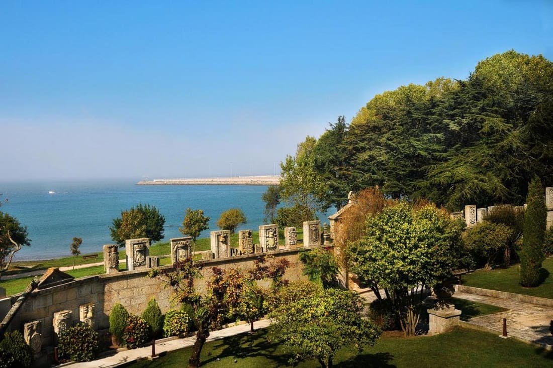 A view of the ocean from outside the luxury hotel with greenery and blue skies.
