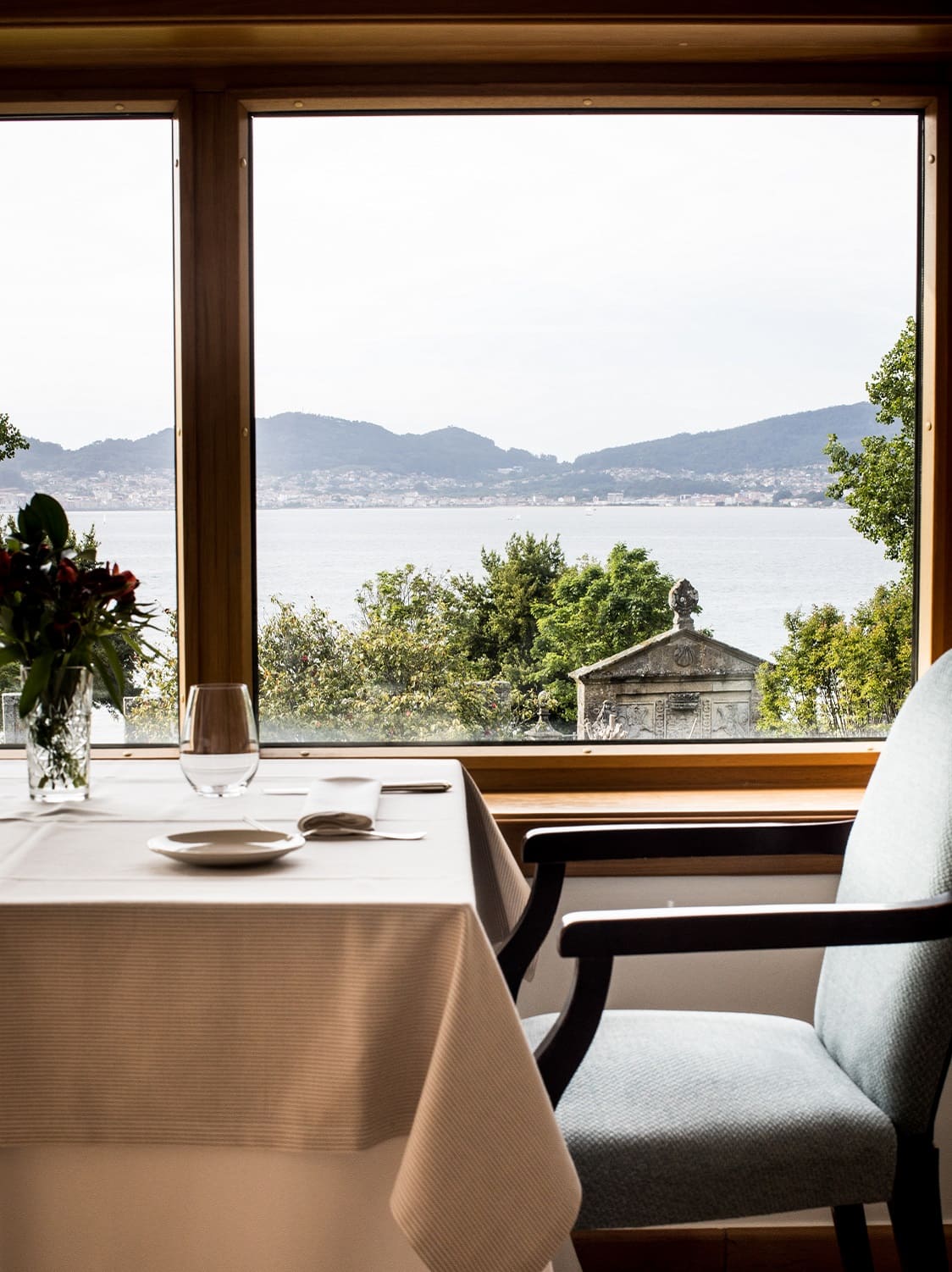 The restaurant in the luxury hotel with a set table and a window showing the views of the mountains and water.
