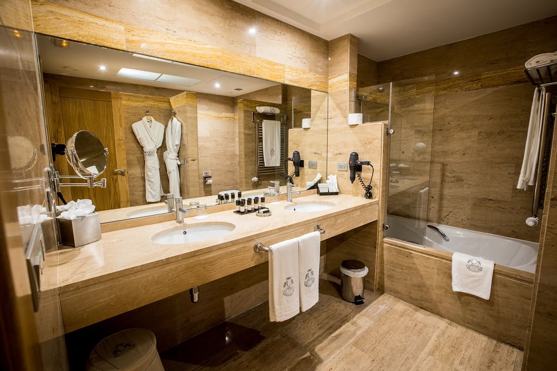 A bathroom in the luxury hotel with a double sink, a large mirror and a bath.