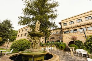 A view of the exterior of the luxury hotel with a water feature in the foreground.