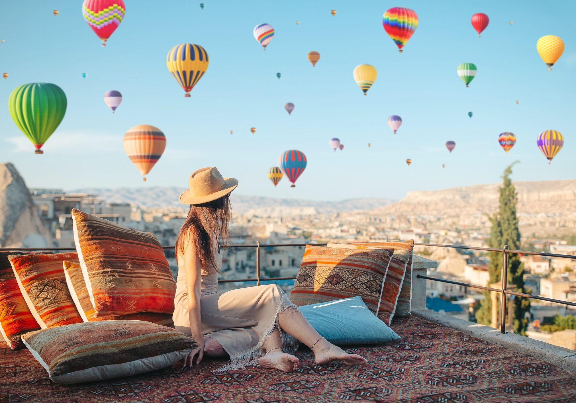 Young woman travelling solo in Cappadocia. Woman on a rooftop with air balloons in Goreme in Cappadocia, Turkey