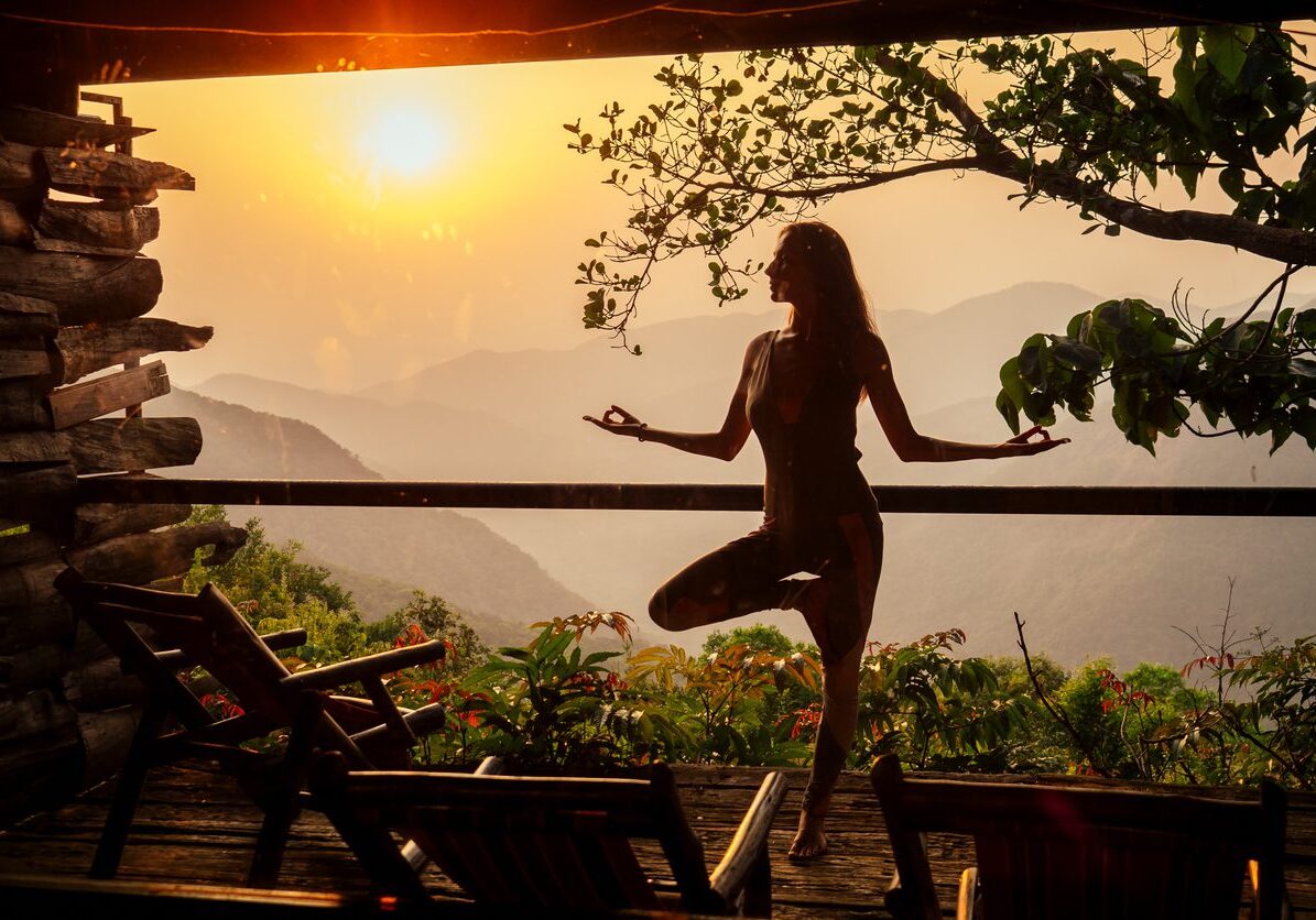 woman in tropical open yoga studio place a view outside to the hills while sunset.girl in eco hotel panoramic windows enjoying solitude with nature Kerala India wildernest resort