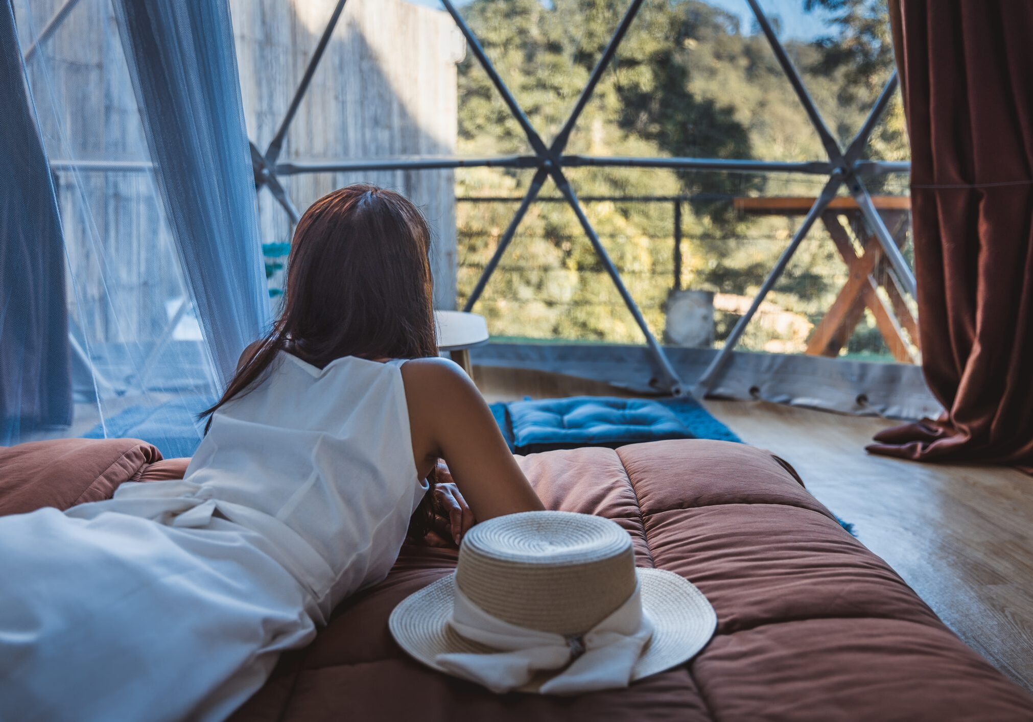 Woman travelling alone, is alone in a hotel room, looks out of the window.